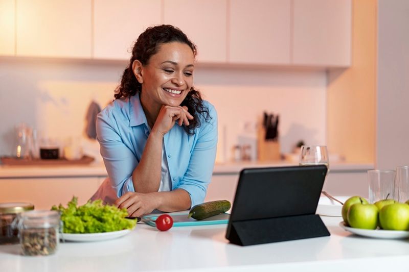 A lady in the kitchen working and communicating by using her tab