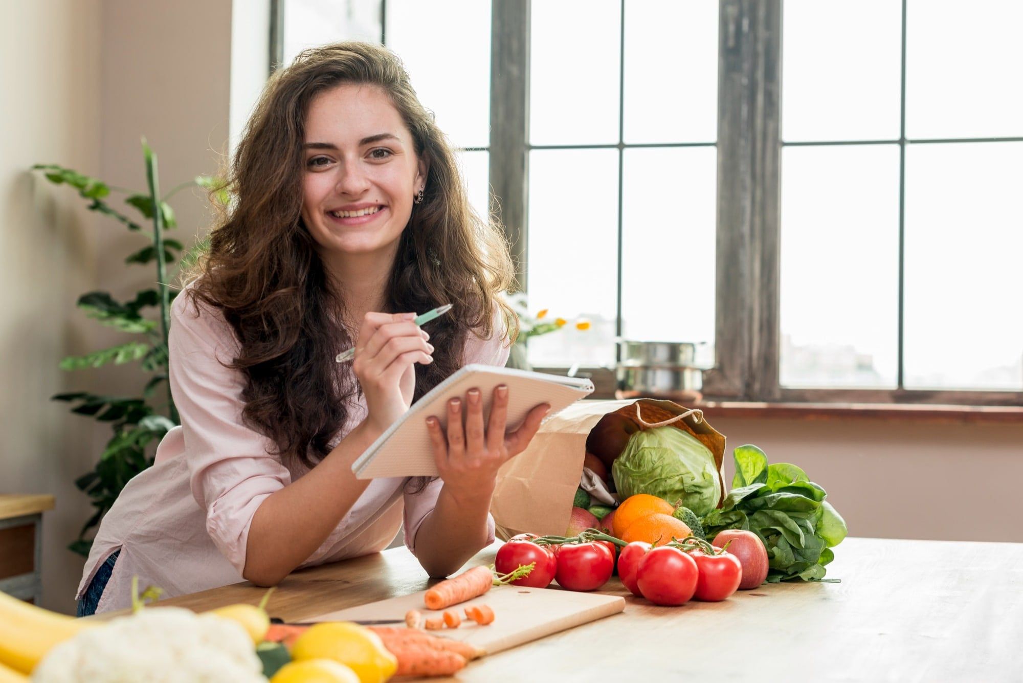 Woman in the kitchen happy and noting down things in her notepad