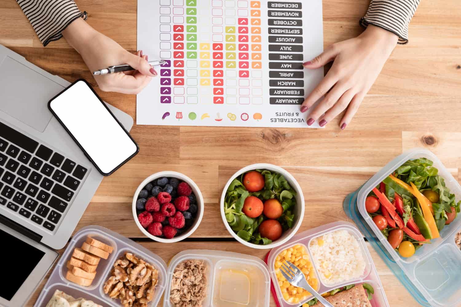 Woman putting ticks on a monthly vegetable and fruit tracker 