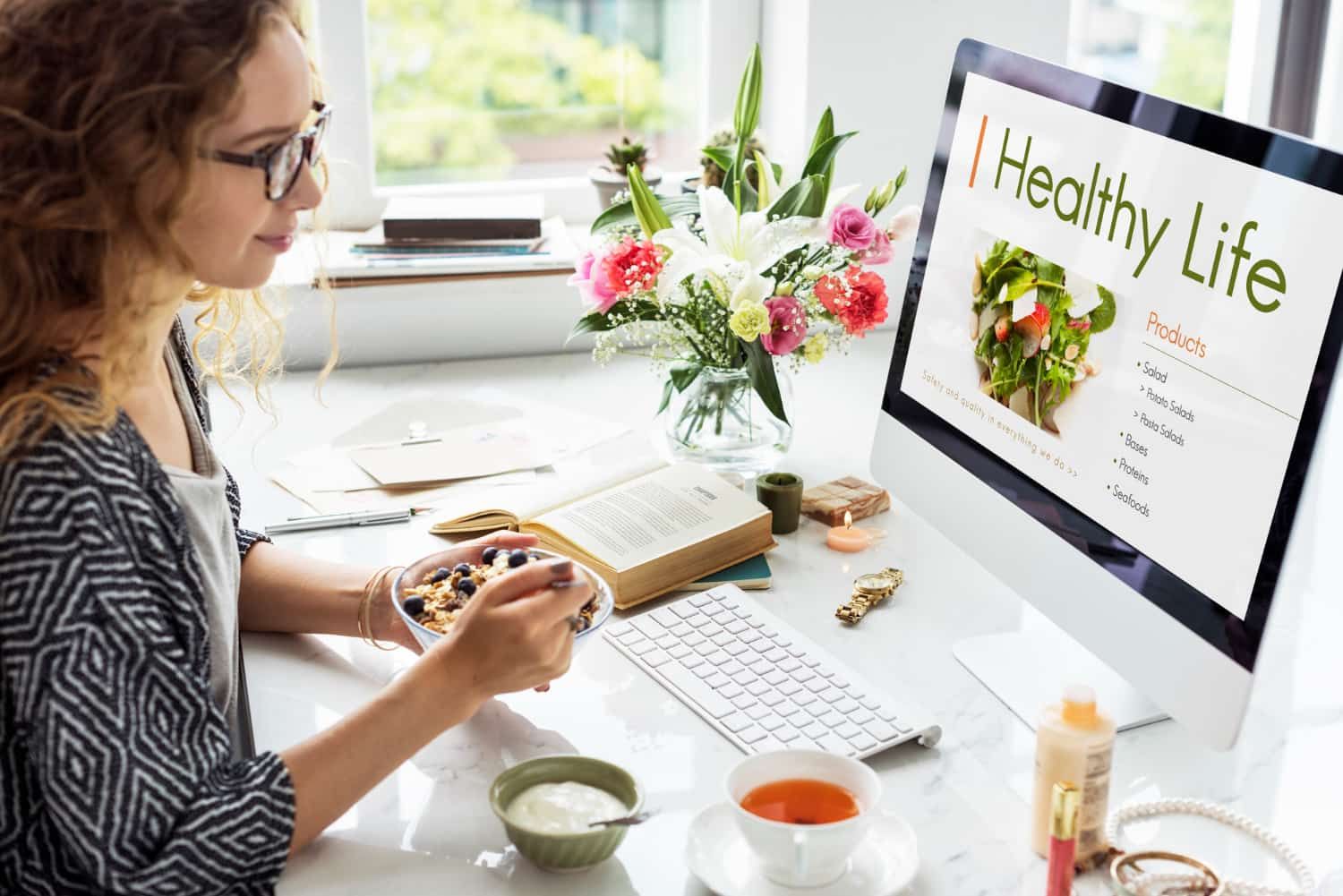 Woman working on her work desk and eating her breakfast 