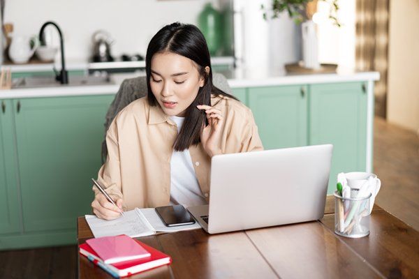 A girl sitting on desk making notes and writing content 