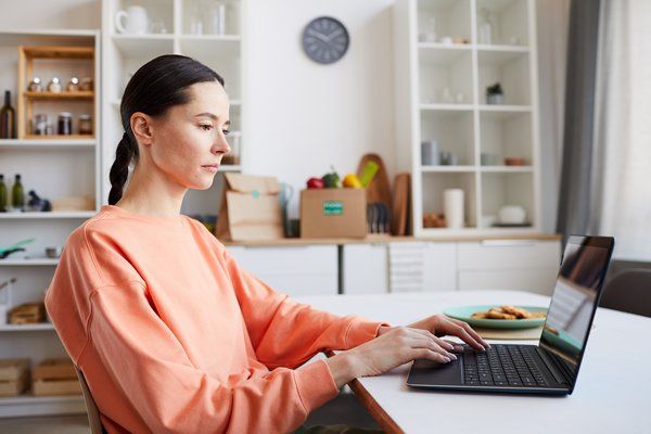 A girl sitting on the desk working on her laptop 